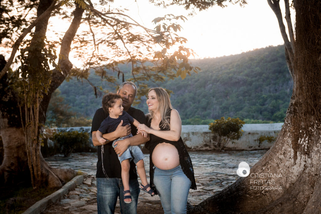 Retrato de gestante com família em ambiente externo ao pôr do sol.