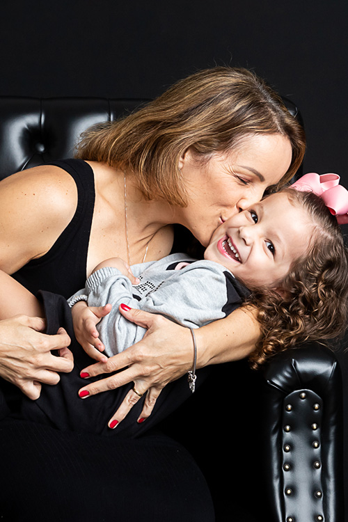 mãe abraçando filha menina no sofa cenário preto ensaio dia das mães